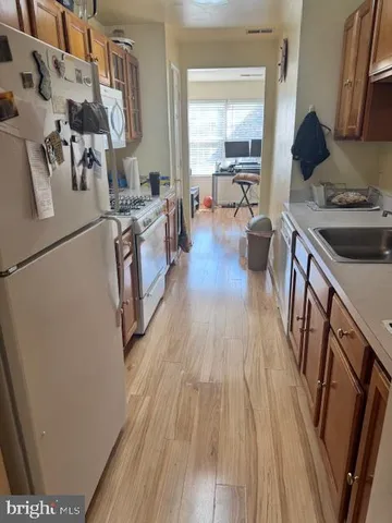 a kitchen with stainless steel appliances a stove a sink a refrigerator and wooden floor