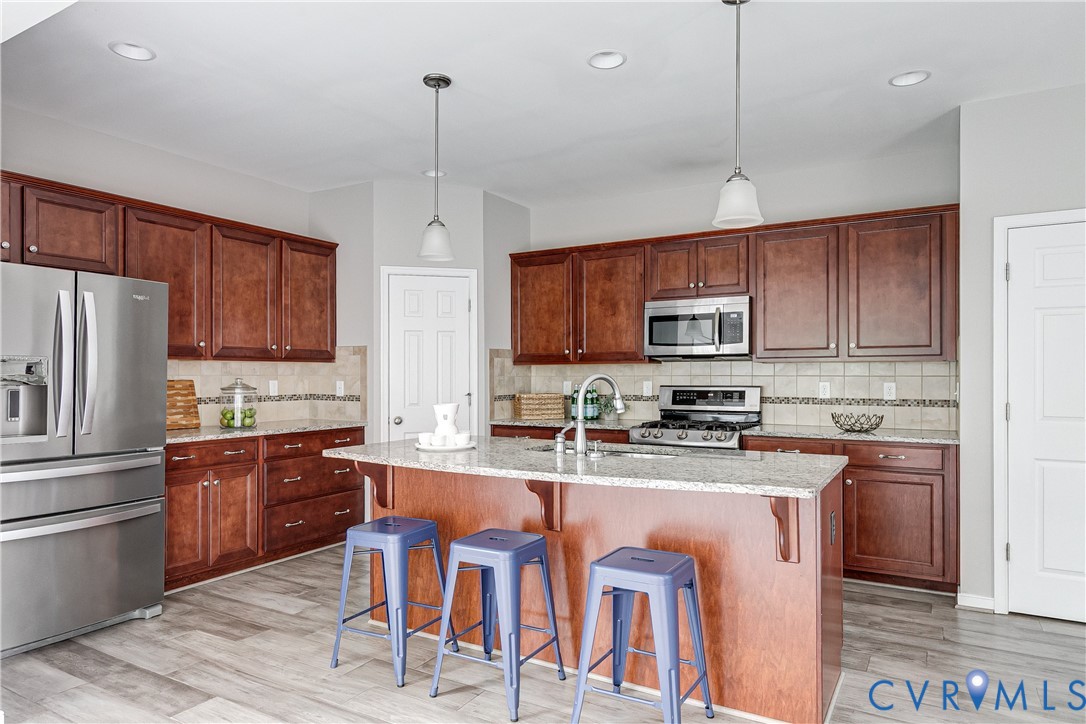 14906 Bridge Spring Drive Midlothian, VA 23113 - Photo 24 of 50 a kitchen with stainless steel appliances granite countertop a stove top oven a refrigerator a sink and dishwasher with wooden floor
