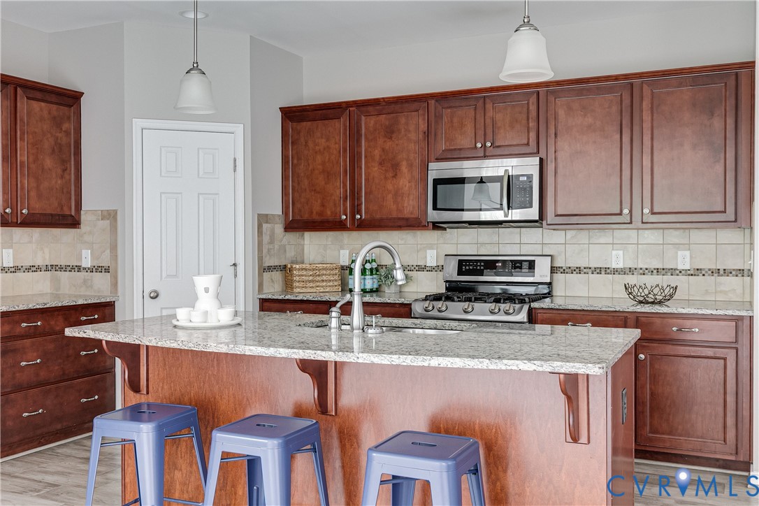 14906 Bridge Spring Drive Midlothian, VA 23113 - Photo 25 of 50 a kitchen with stainless steel appliances granite countertop a stove a sink a microwave a refrigerator and cabinets