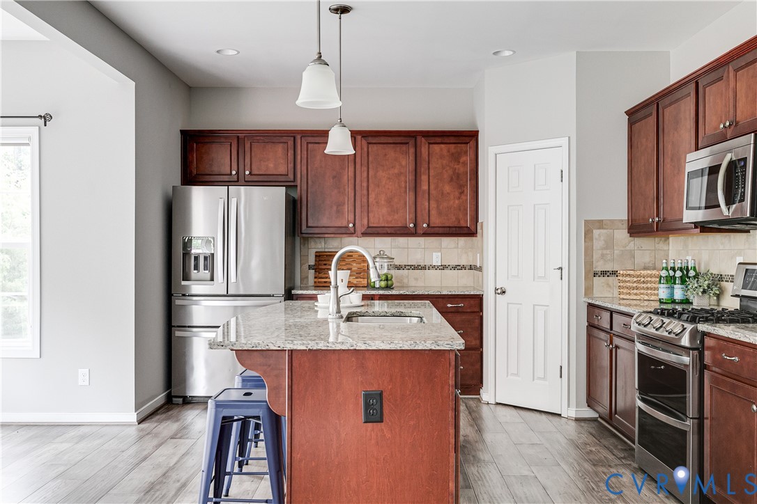 14906 Bridge Spring Drive Midlothian, VA 23113 - Photo 28 of 50 a kitchen with stainless steel appliances granite countertop a refrigerator a stove top oven a sink dishwasher and white cabinets with wooden floor