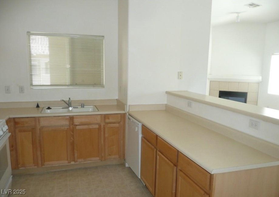 8725 West Flamingo Road, Unit 226 Las Vegas, NV 89147 - Photo 4 of 7 Kitchen with a peninsula, stove, white dishwasher, light countertops, and a tile fireplace