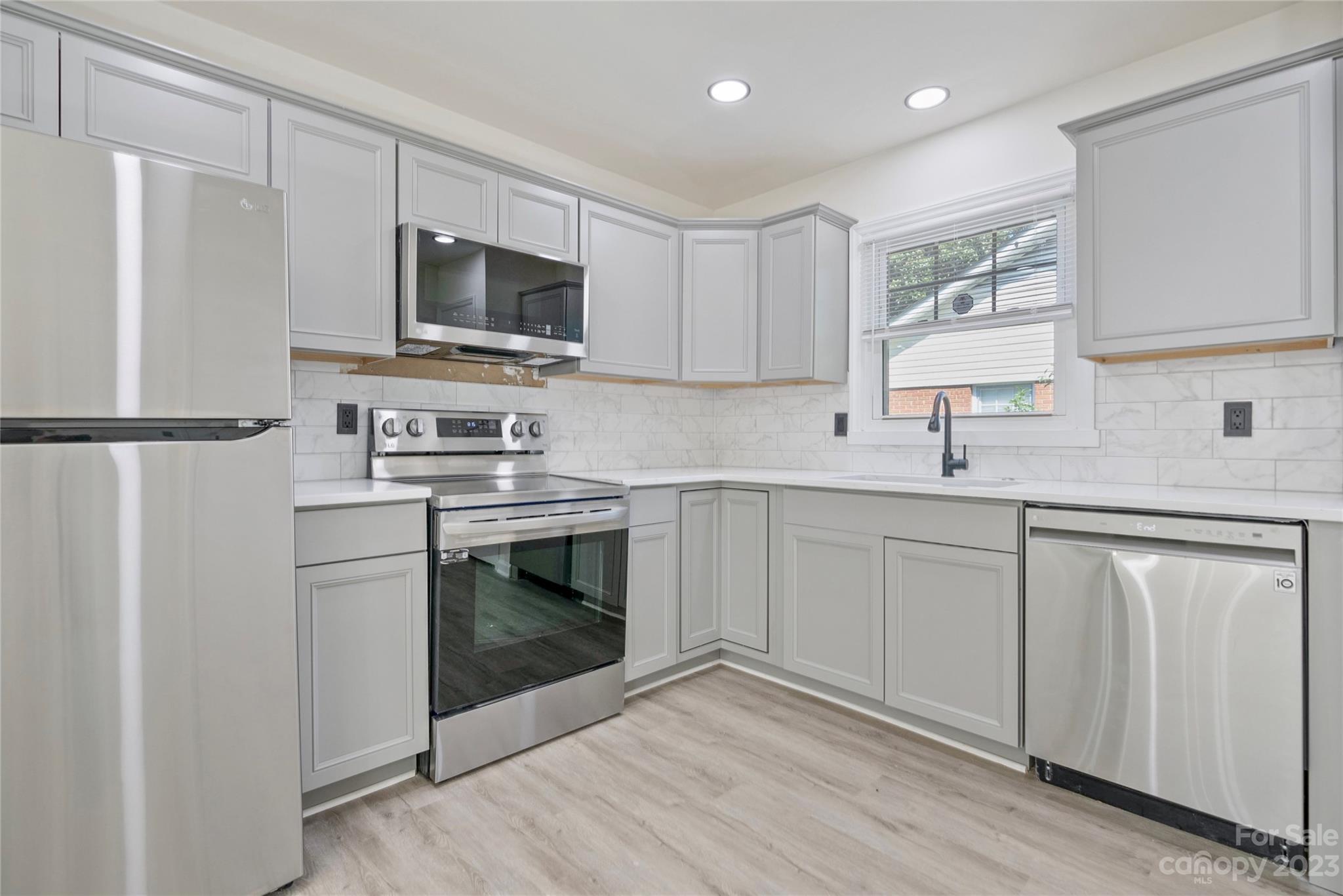 1424 Echo Glen Road Charlotte, NC 28213 - Photo 11 of 26 a kitchen with white cabinets stainless steel appliances and a refrigerator