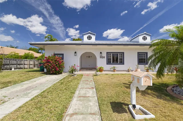 a view of house with swimming pool outdoor seating and covered with palm trees
