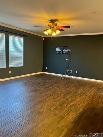 a view of an empty room with chandelier fan