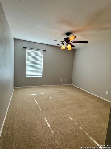 an empty room with a window and a ceiling fan