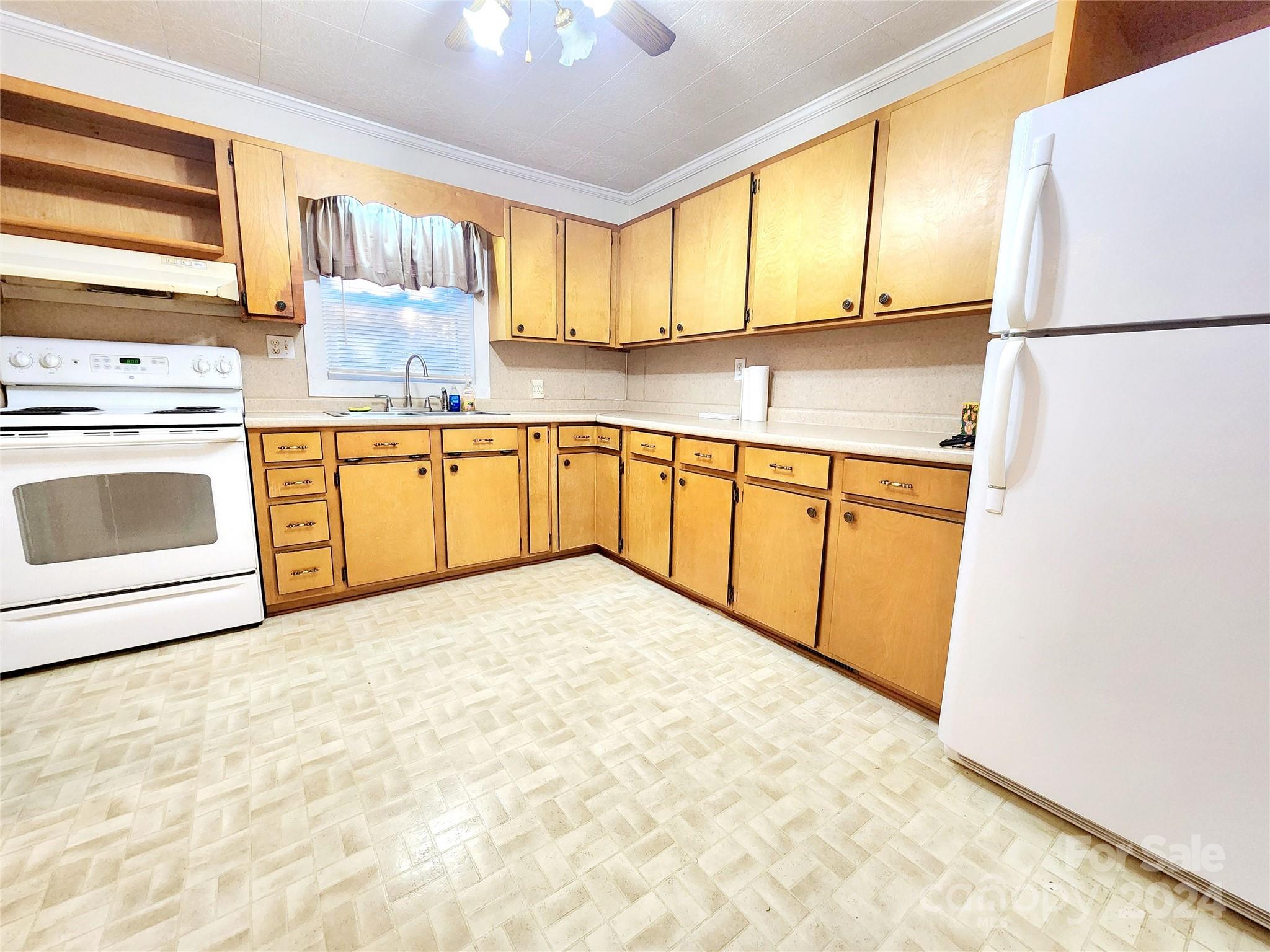 3004 Goble Road Hiddenite, NC 28636 - Photo 3 of 17 a kitchen with granite countertop a refrigerator a stove a sink dishwasher and wooden cabinets with wooden floor