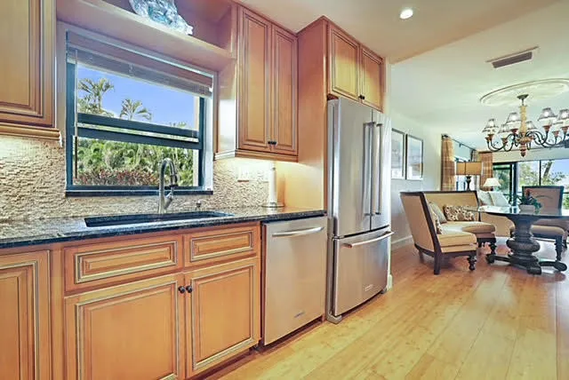 a kitchen with stainless steel appliances granite countertop a refrigerator and a stove top oven