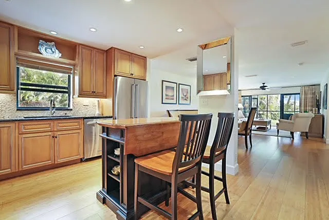 a kitchen with stainless steel appliances granite countertop a table chairs refrigerator and sink