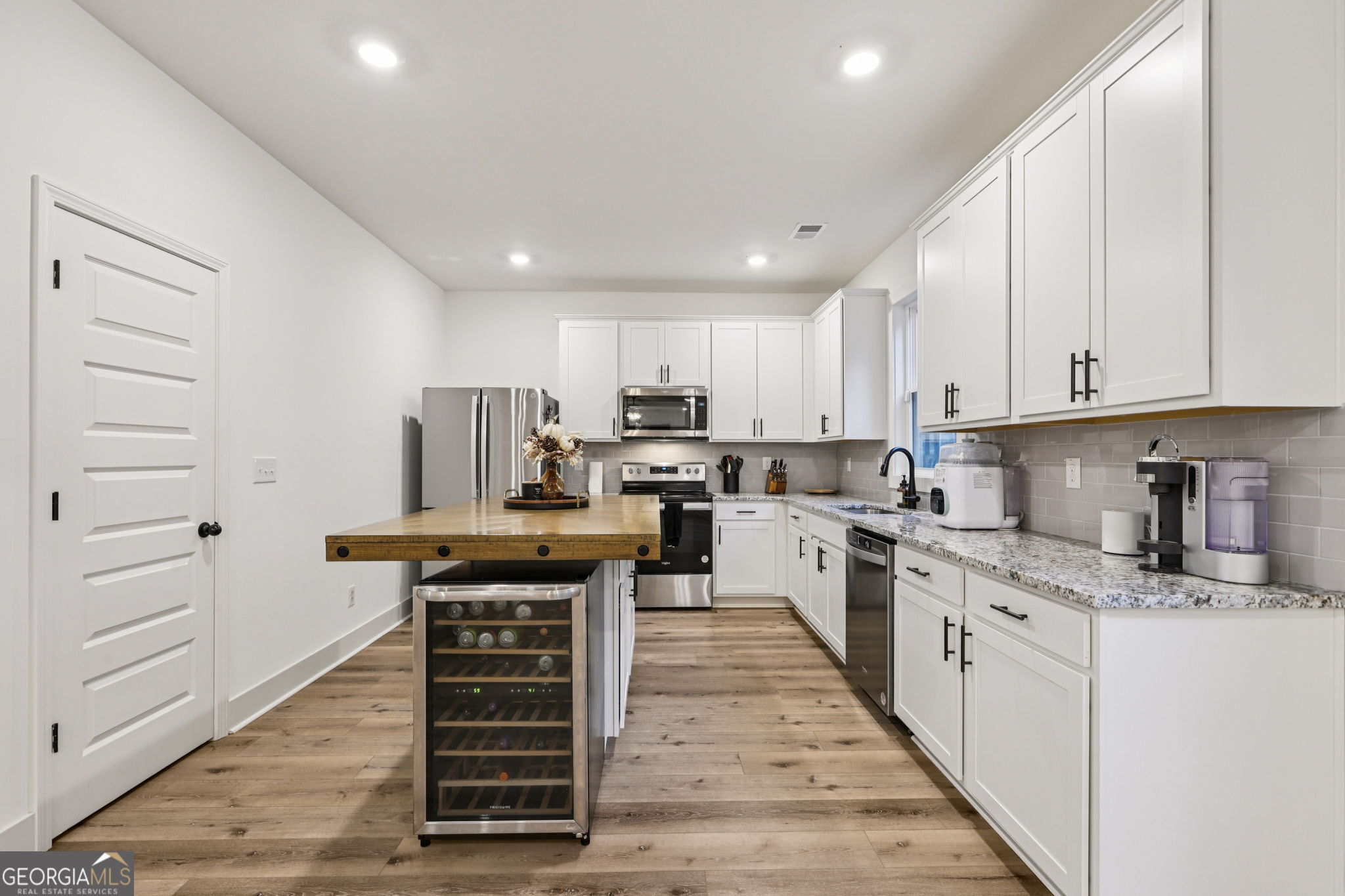 779 Millen Road Monticello, GA 31064 - Photo 16 of 52 a kitchen with kitchen island granite countertop a stove top oven a sink dishwasher and white cabinets with wooden floor