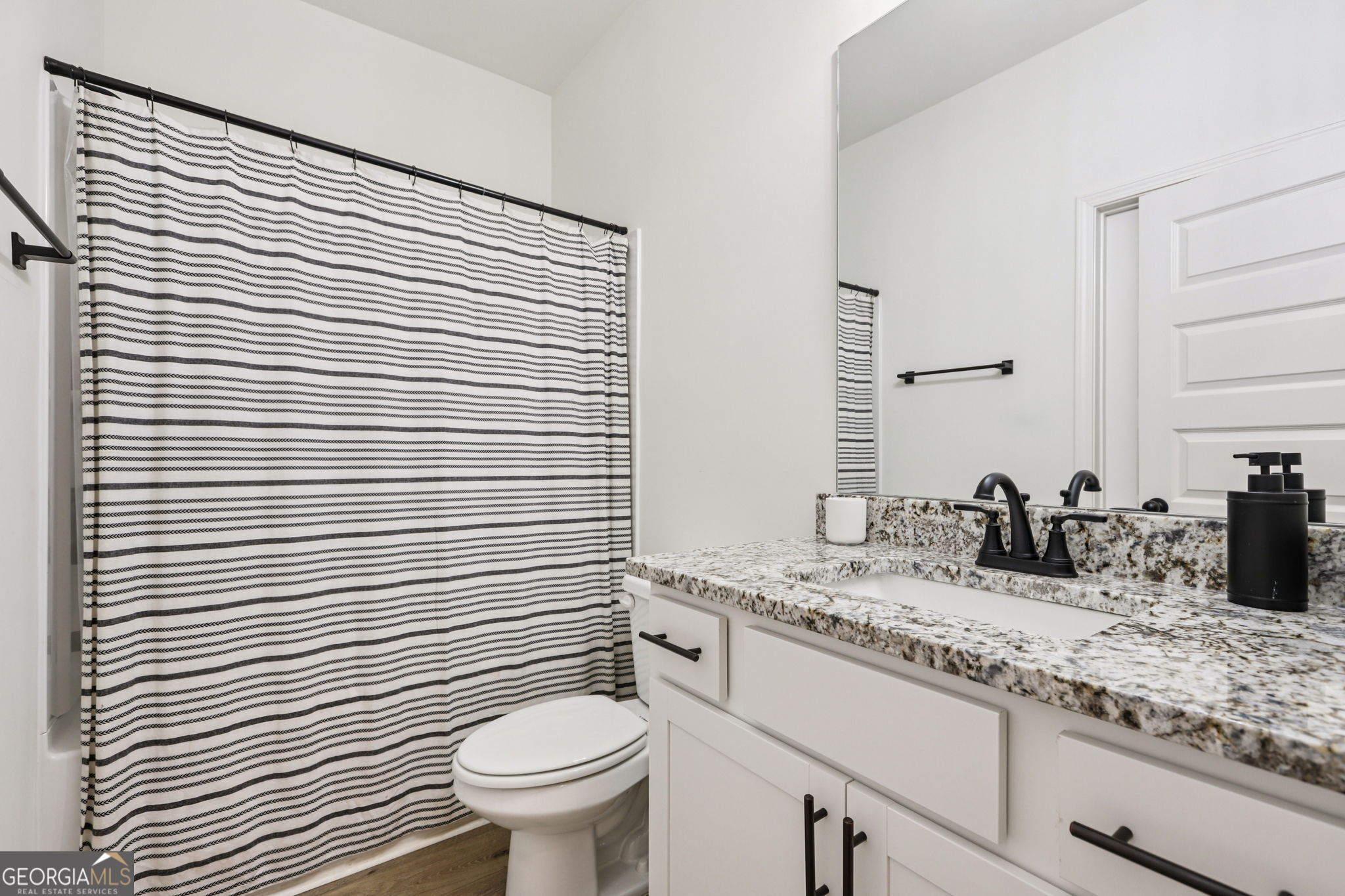 779 Millen Road Monticello, GA 31064 - Photo 22 of 52 a bathroom with a granite countertop toilet a sink and a mirror