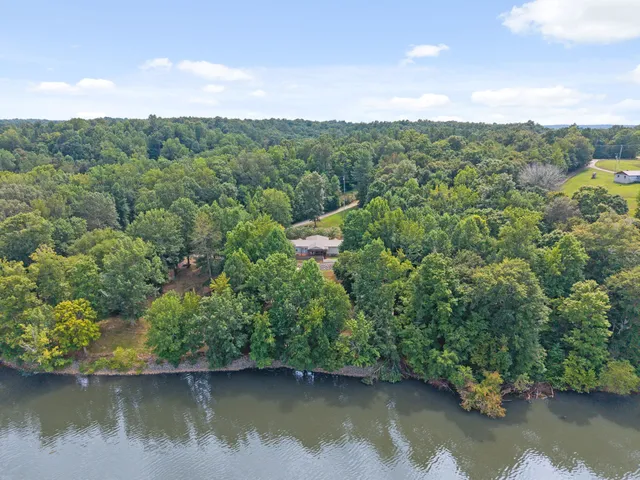 a view of a white house with a big yard and large trees