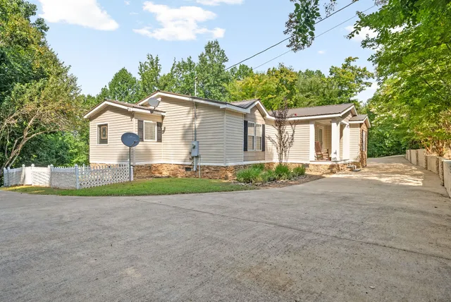 a view of a white house with a small yard and large tree