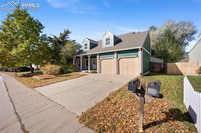 103 Saddlemountain Road Colorado Springs, CO 80919 - Photo 30 of 30 New england style home with brick siding, driveway, a porch, a garage, and roof with shingles