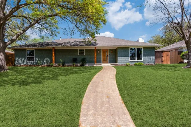 a front view of a house with a garden and trees