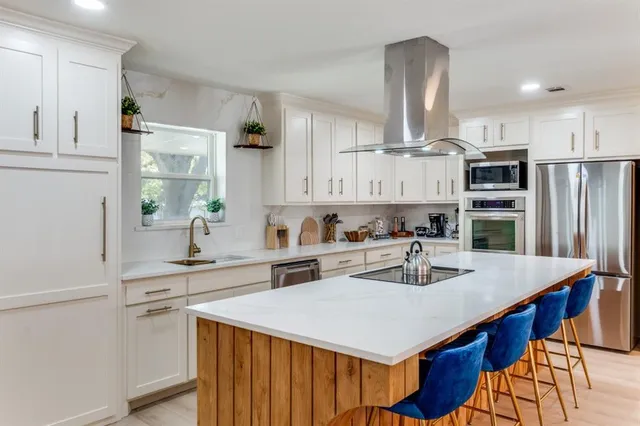 a kitchen with stainless steel appliances a sink a stove a refrigerator and white cabinets