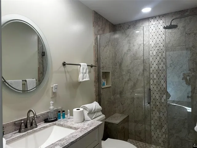a bathroom with a granite countertop sink toilet and shower