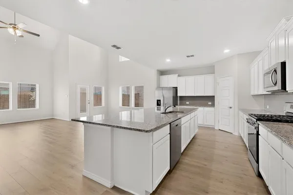 a large kitchen with stainless steel appliances granite countertop a lot of counter space and wooden floor