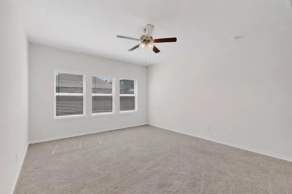 an empty room with windows and ceiling fan