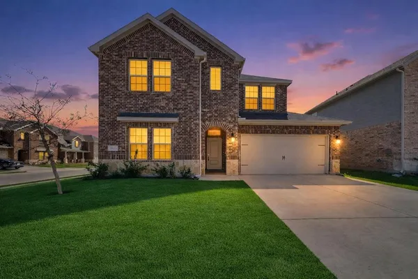 a front view of a house with a yard and trees