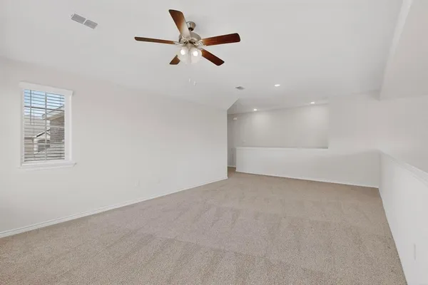 an empty room with ceiling fan and windows