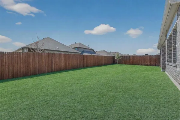 a view of a backyard with a barbeque and wooden fence