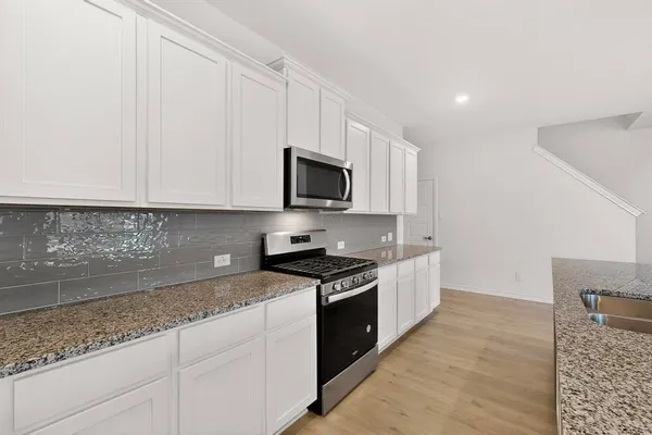a kitchen with granite countertop cabinets stainless steel appliances and a counter space
