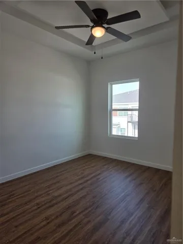 an empty room with wooden floor ceiling fan and window