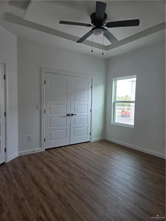 an empty room with wooden floor chandelier fan and windows
