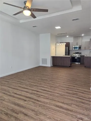 a view of kitchen and empty room with wooden floor