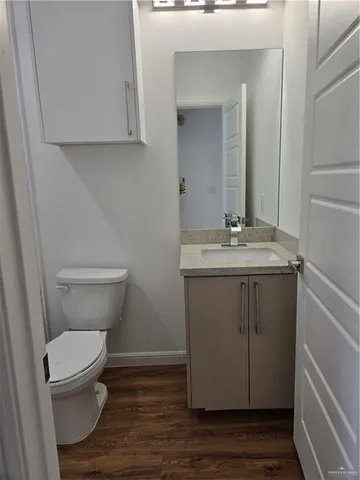 a bathroom with a toilet a sink and wooden floor