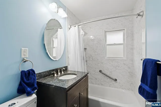 a bathroom with a granite countertop sink a mirror and a bathtub