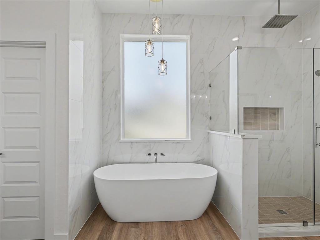 328 Slimp Bluff Azle, TX 76020 - Photo 17 of 30 Spacious bathroom featuring a freestanding soaking tub with wall-mounted faucet, a walk-in shower with glass enclosure, and wood-finish flooring