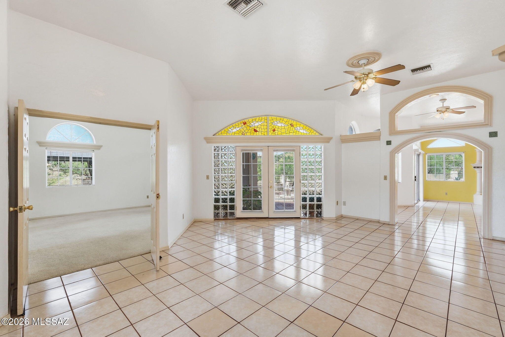 1242 Vista Court Rio Rico, AZ 85648 - Photo 4 of 51 As you step inside, you are welcomed by a spacious entertaining room filled with abundant natural light that streams through the windows, creating a warm and inviting atmosphere. Beautiful tile flooring adds both style and durability while making maintenance a breeze. Serving as the heart of the home, this central gathering space provides seamless access to the primary bedroom, living room, kitchen, and office, while elegant French doors invite you to step outside and enjoy the backyard. Whether hosting family and friends or simply enjoying everyday living, this versatile space offers both comfort and convenience with an open, flowing layout.