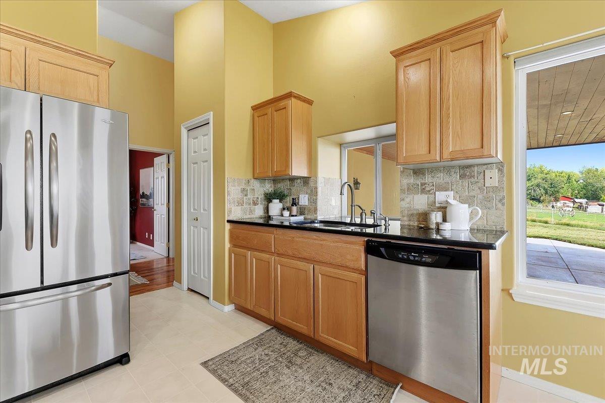 7900 Labor Camp Road Caldwell, ID 83607 - Photo 11 of 45 Kitchen featuring wood cabinetry, stainless steel appliances, black countertops, and a tiled backsplash