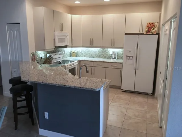 a kitchen with stainless steel appliances granite countertop a sink and a refrigerator