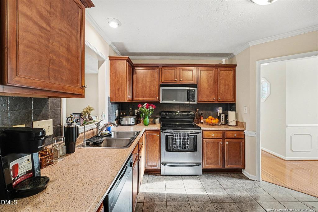 831 Raspberry Road Stedman, NC 28391 - Photo 13 of 35 a kitchen with stainless steel appliances granite countertop a stove top oven a sink dishwasher and a refrigerator with wooden cabinets