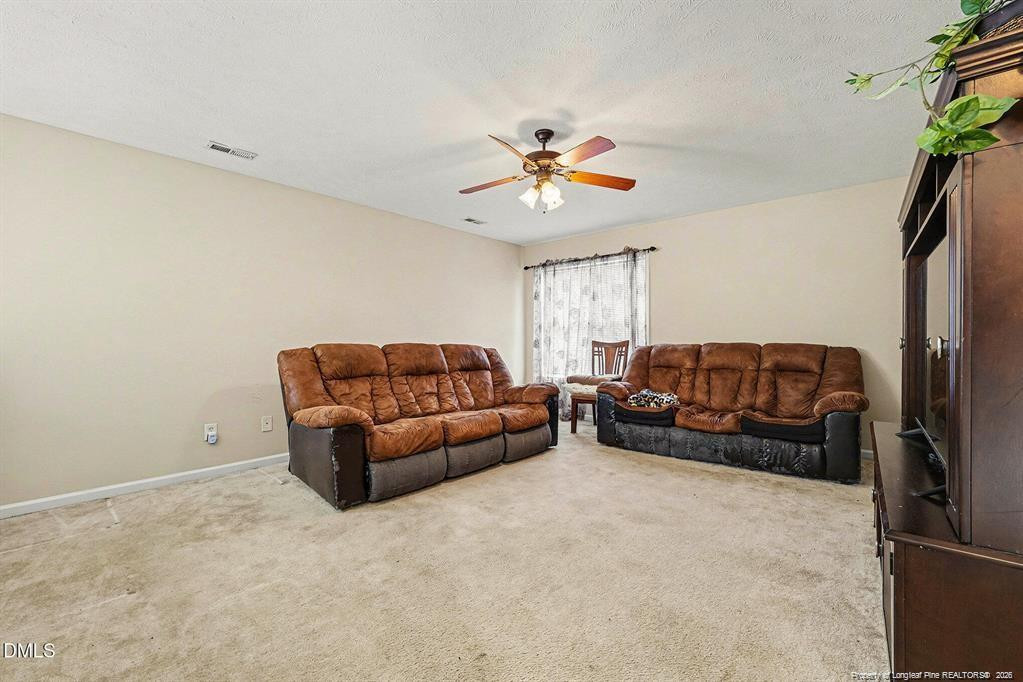 831 Raspberry Road Stedman, NC 28391 - Photo 25 of 35 a living room with furniture a ceiling fan and a rug