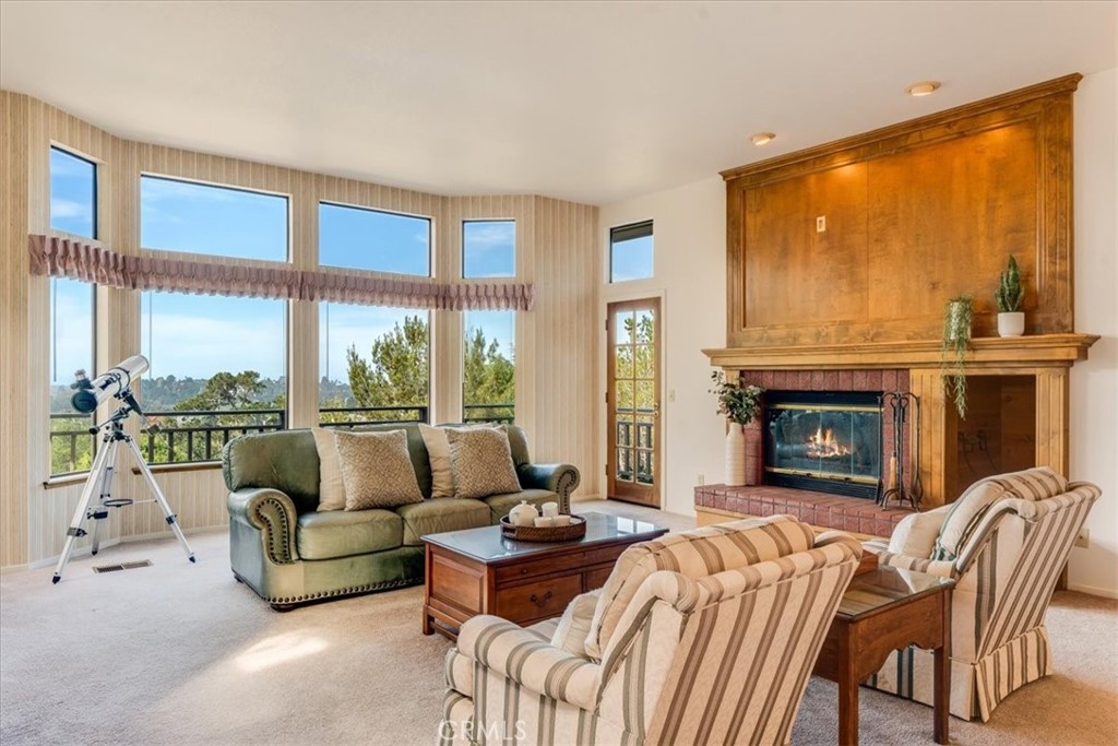 3171 Rogers Road Cambria, CA 93428 - Photo 16 of 73 a living room with furniture a fireplace and floor to ceiling windows