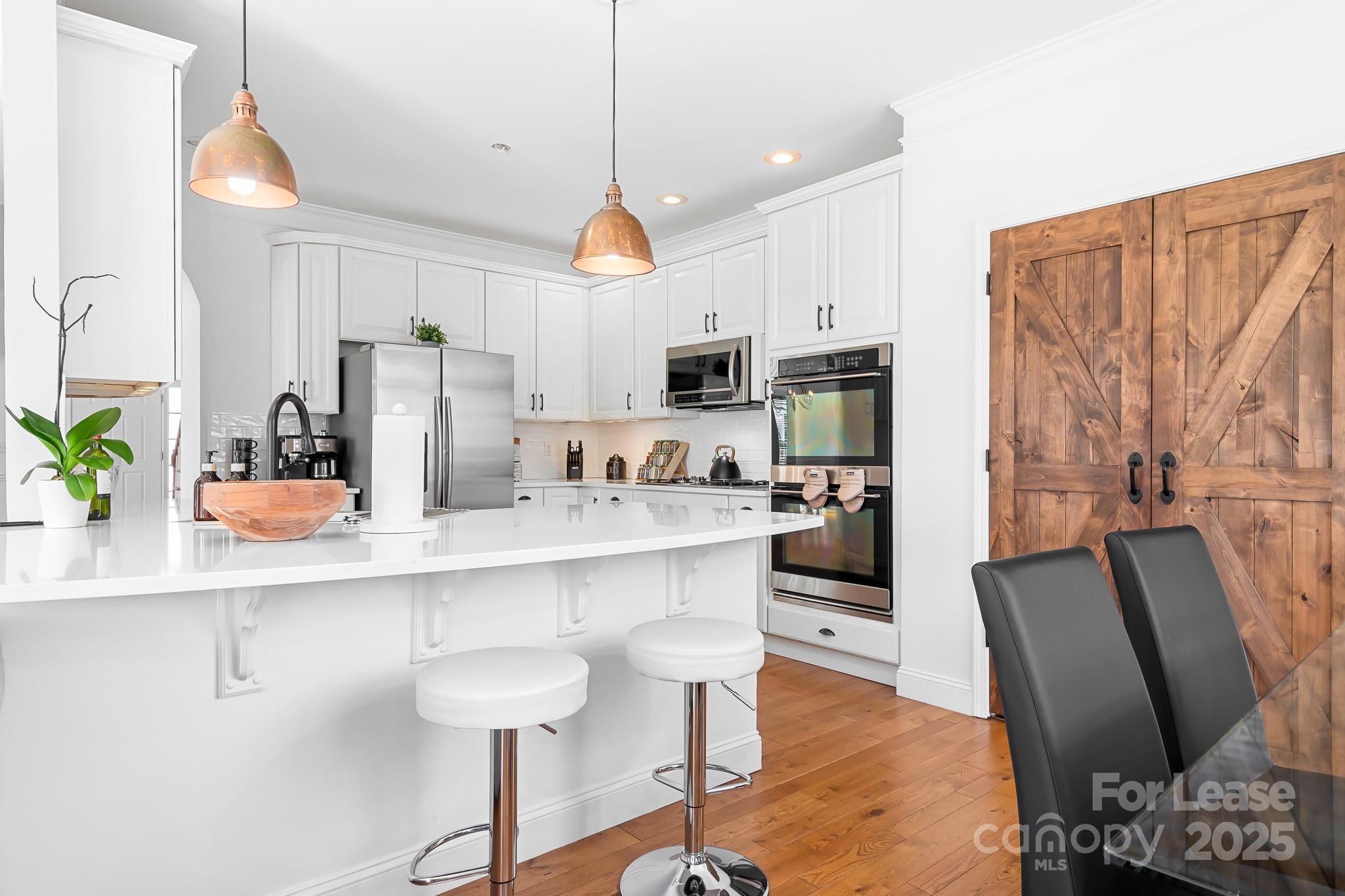7277 Willowbrook Drive Denver, NC 28037 - Photo 12 of 33 a kitchen with stainless steel appliances a dining table chairs refrigerator and microwave