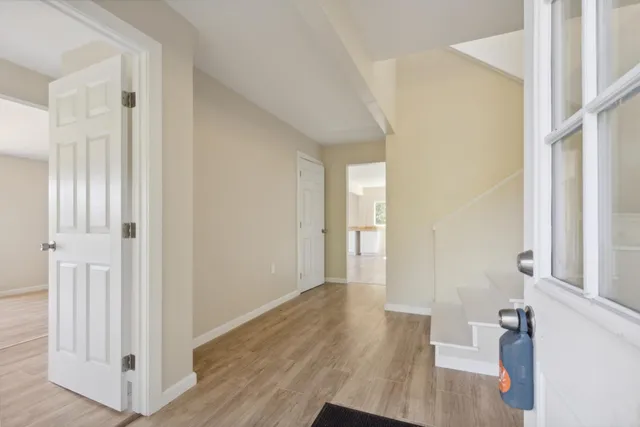 a view of an empty room with window and wooden floor