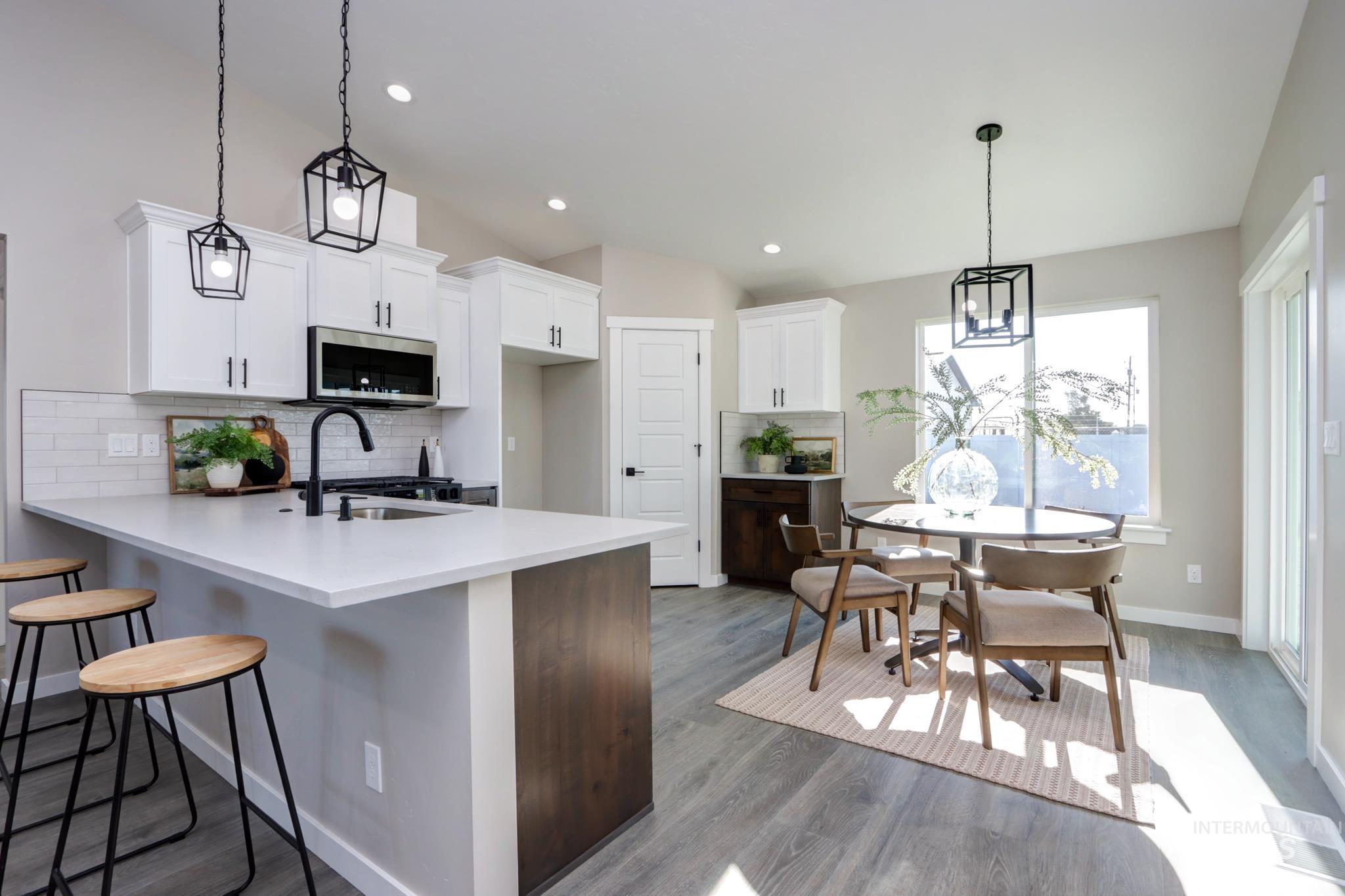 848 North 5th Street Nyssa, OR 97913 - Photo 3 of 49 Open-concept kitchen and dining area featuring white shaker cabinetry, stainless steel microwave, matte black faucet, and wood-finish flooring