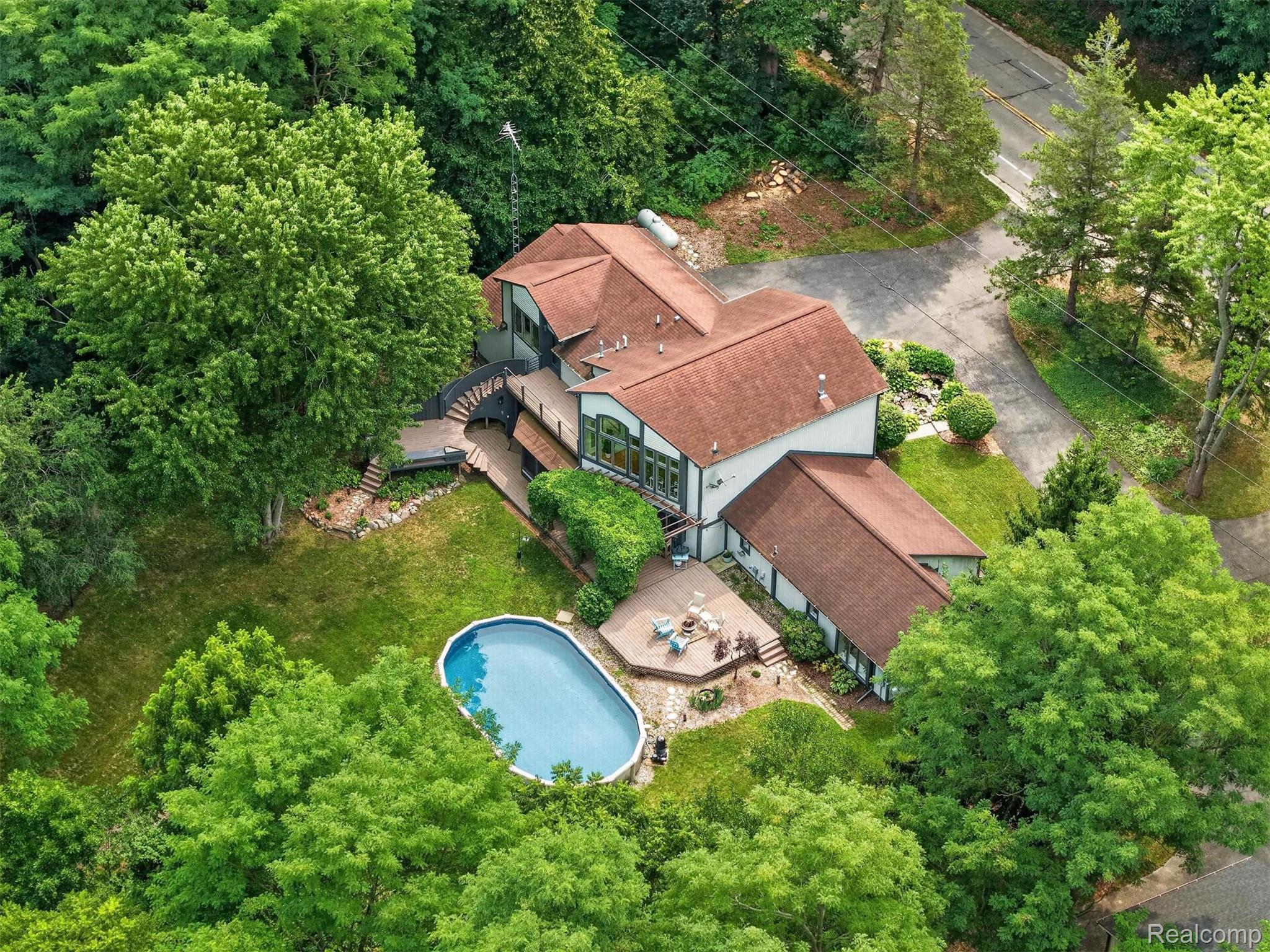 9319 Faussett Road Fenton, MI 48430 - Photo 66 of 70 Multiple-gable roofline residence with extensive decking, an oval swimming pool, and stone paver patio