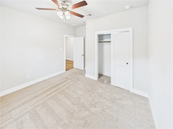 an empty room with closet and a ceiling fan