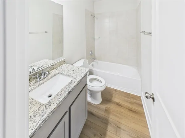 a bathroom with a granite countertop sink a toilet and bathtub
