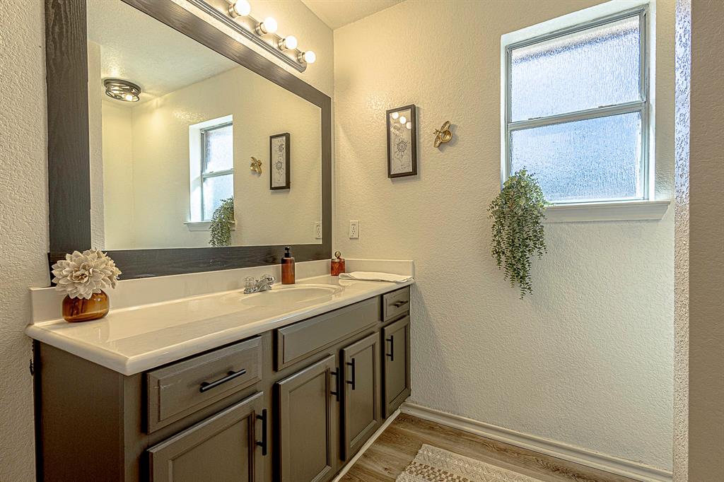 10812 Lilry Road Waco, TX 76708 - Photo 16 of 25 Bathroom with a textured wall, vanity, and dark wood-style floors