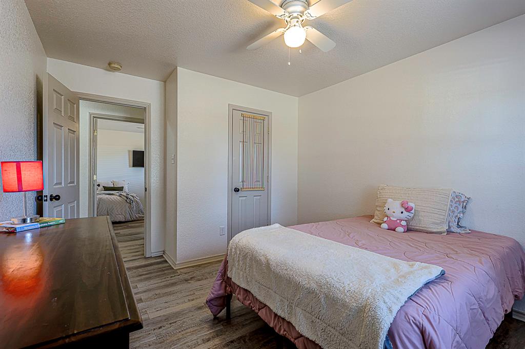 10812 Lilry Road Waco, TX 76708 - Photo 19 of 25 Bedroom with a textured ceiling, wood finished floors, ceiling fan, and a textured wall