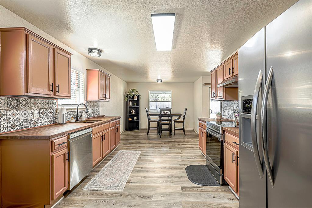 10812 Lilry Road Waco, TX 76708 - Photo 5 of 25 Kitchen featuring stainless steel appliances, decorative backsplash, a textured ceiling, light wood-style flooring, and wood counters