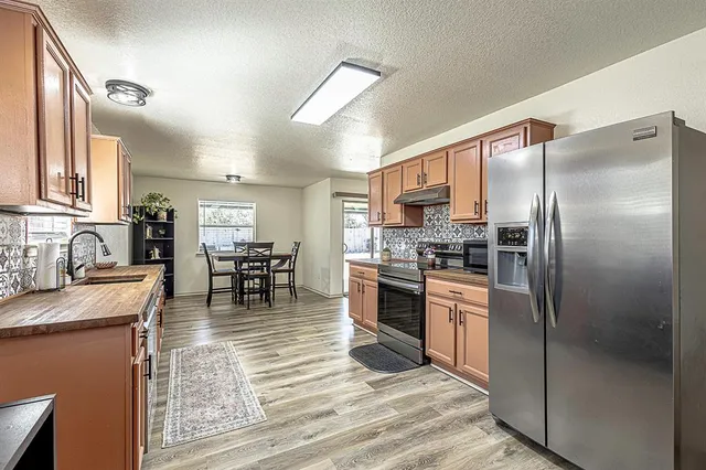 a kitchen with granite countertop a refrigerator stove top oven and sink