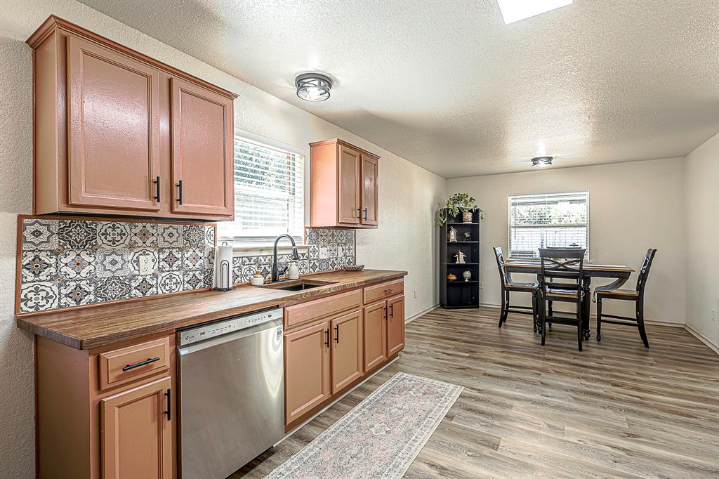 10812 Lilry Road Waco, TX 76708 - Photo 7 of 25 Kitchen featuring a textured ceiling, dishwasher, backsplash, dark wood-style floors, and a textured wall