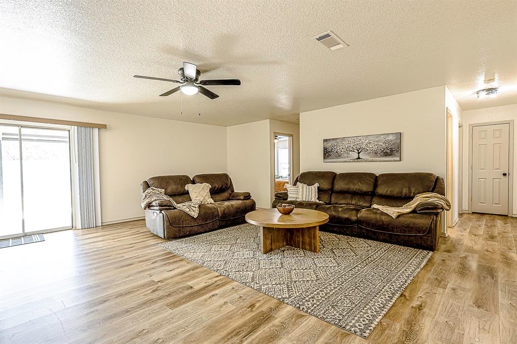 10812 Lilry Road Waco, TX 76708 - Photo 10 of 25 Living room featuring a textured ceiling, light wood-style flooring, and a ceiling fan